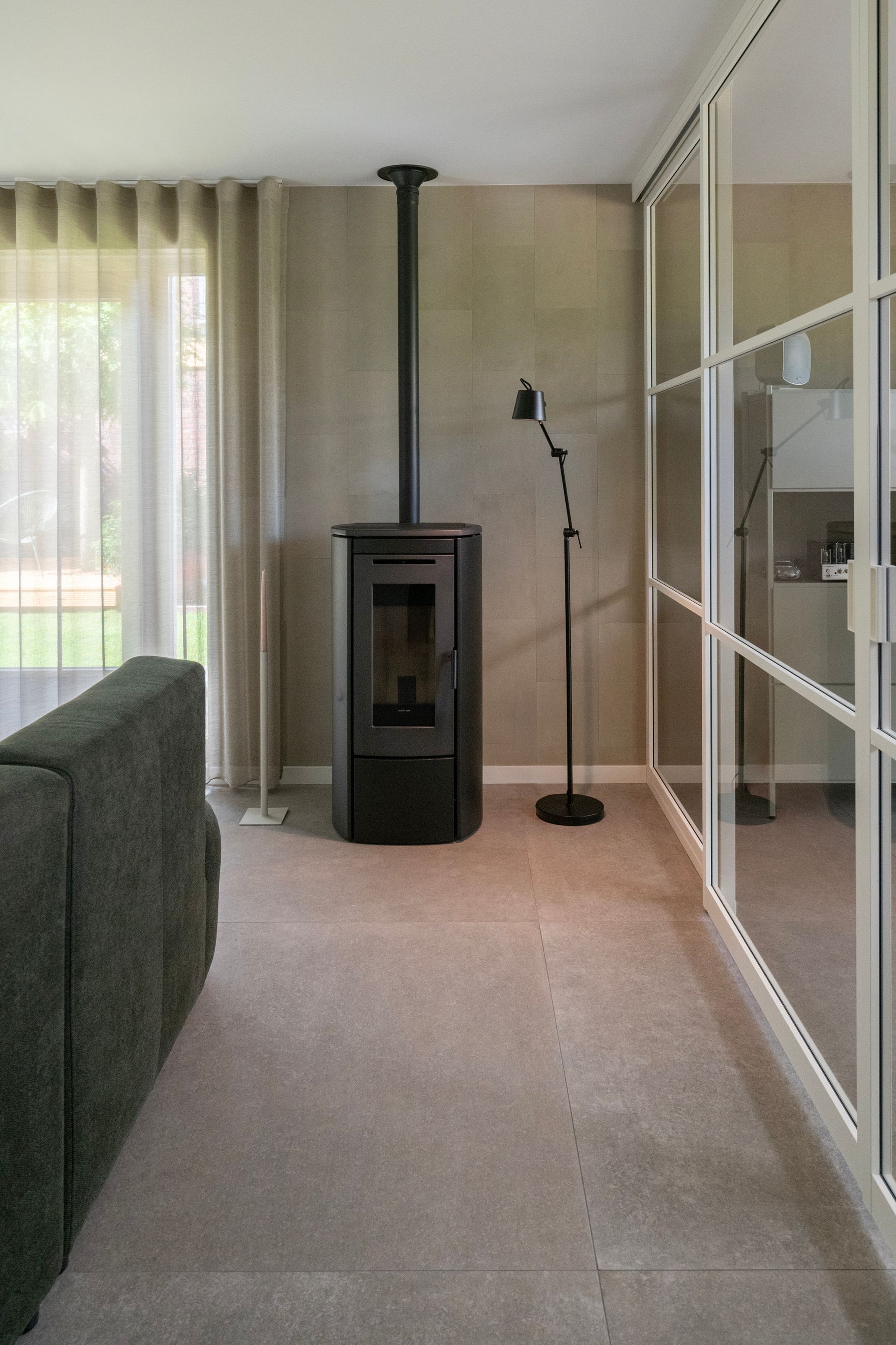 De witte glazen schuifwand zorgt voor een scheiding tussen de woonkamer en de werkkamer.