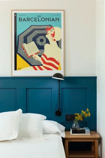 A bedroom with a blue headboard and a poster that says barcelona on it