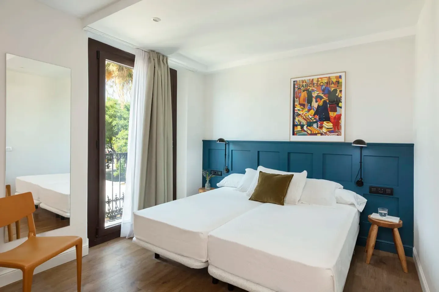 A hotel room with two beds , a chair , a mirror and a balcony.