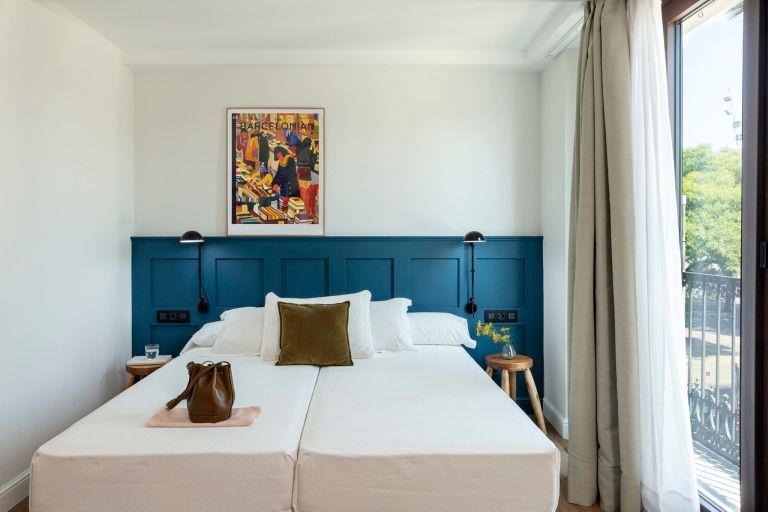 A bedroom with two beds and a blue headboard.