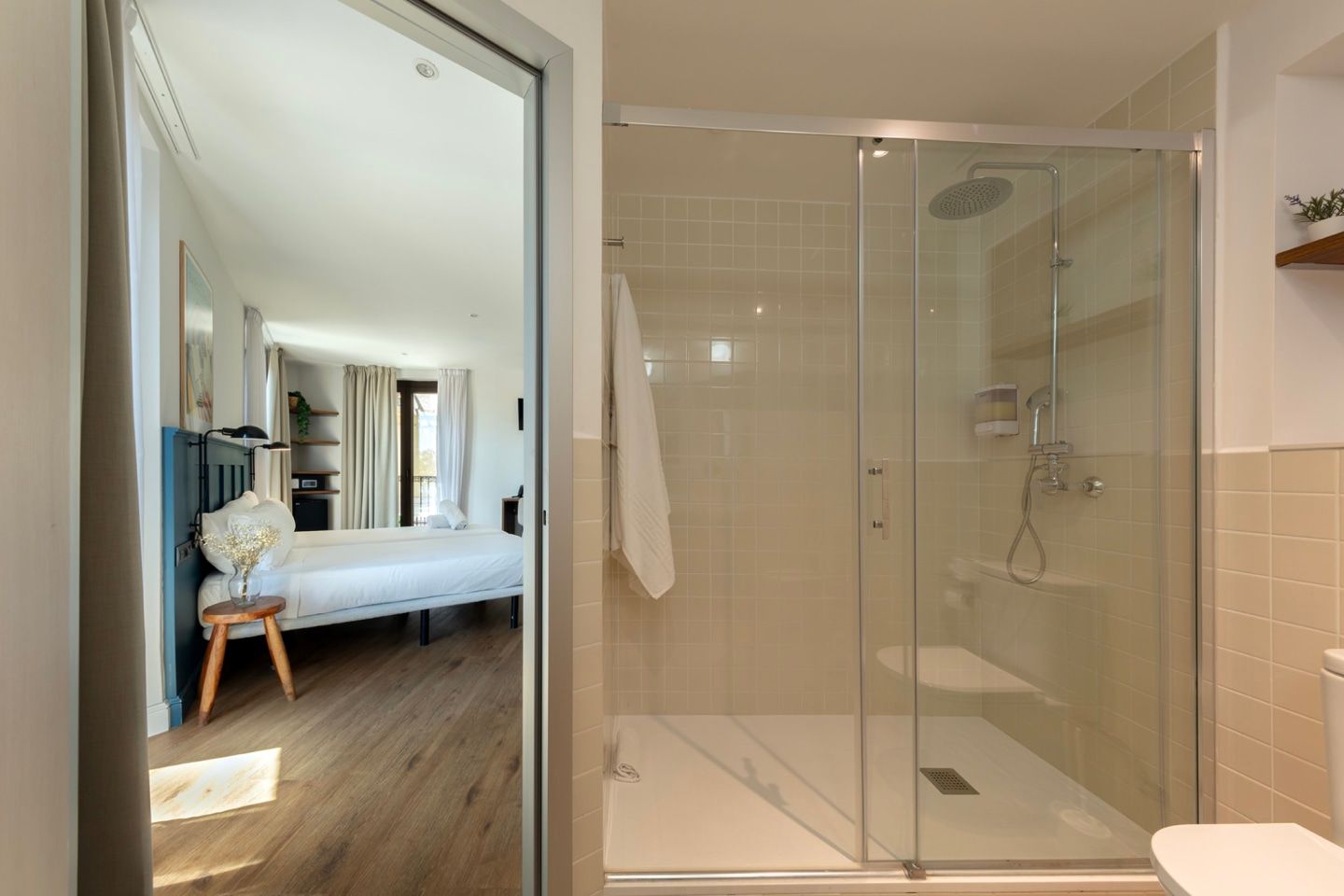 A bathroom with a walk in shower and a bedroom in the background