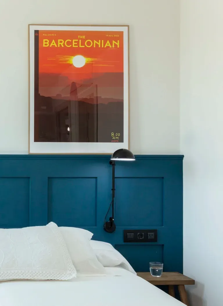 A bed with a blue headboard and a barcelona poster above it