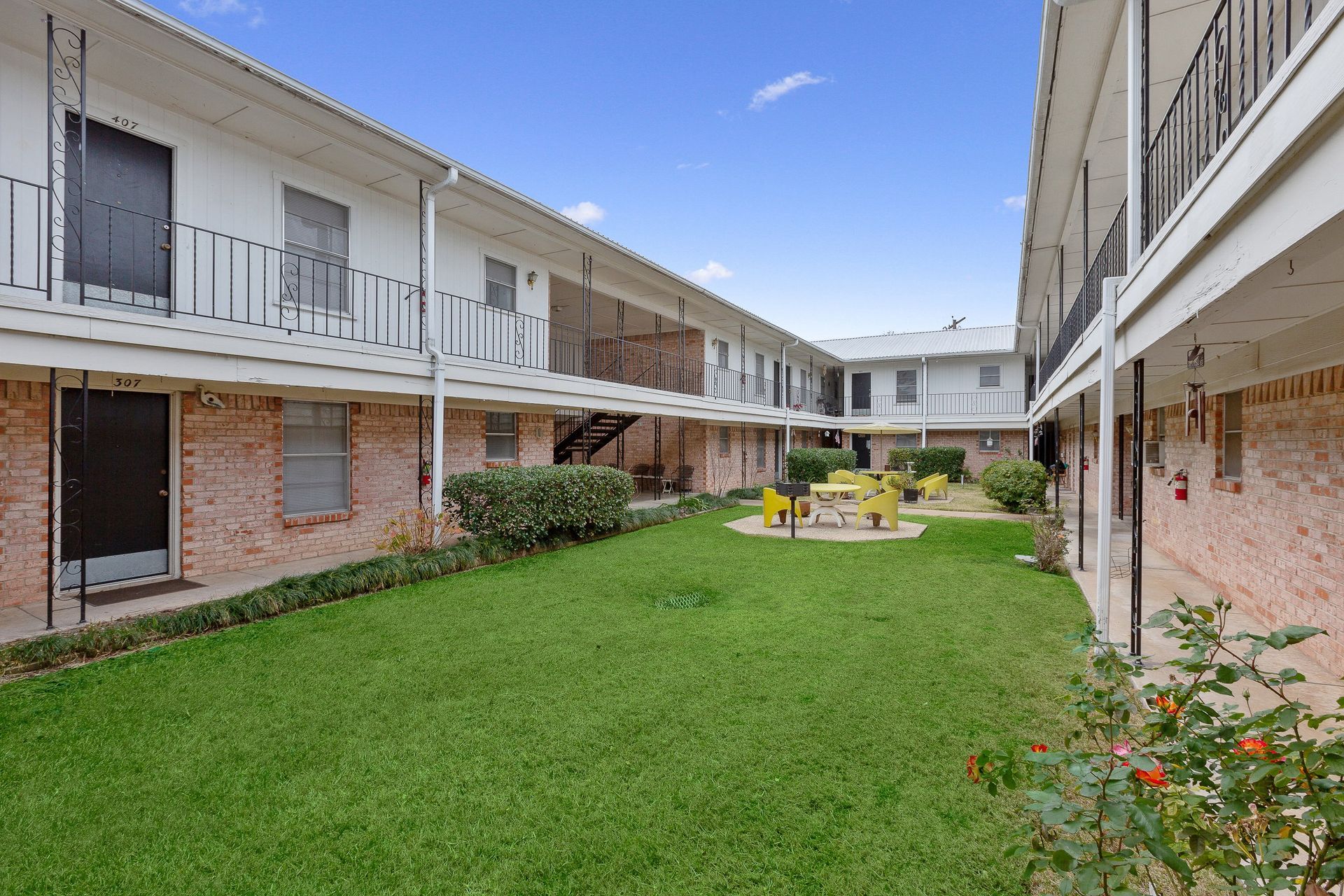A large apartment building with a large lawn in front of it.