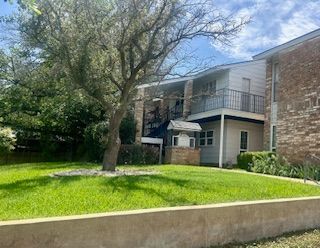 A brick apartment building with a large lawn in front of it.