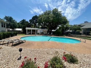 There is a large swimming pool in the backyard of a house.