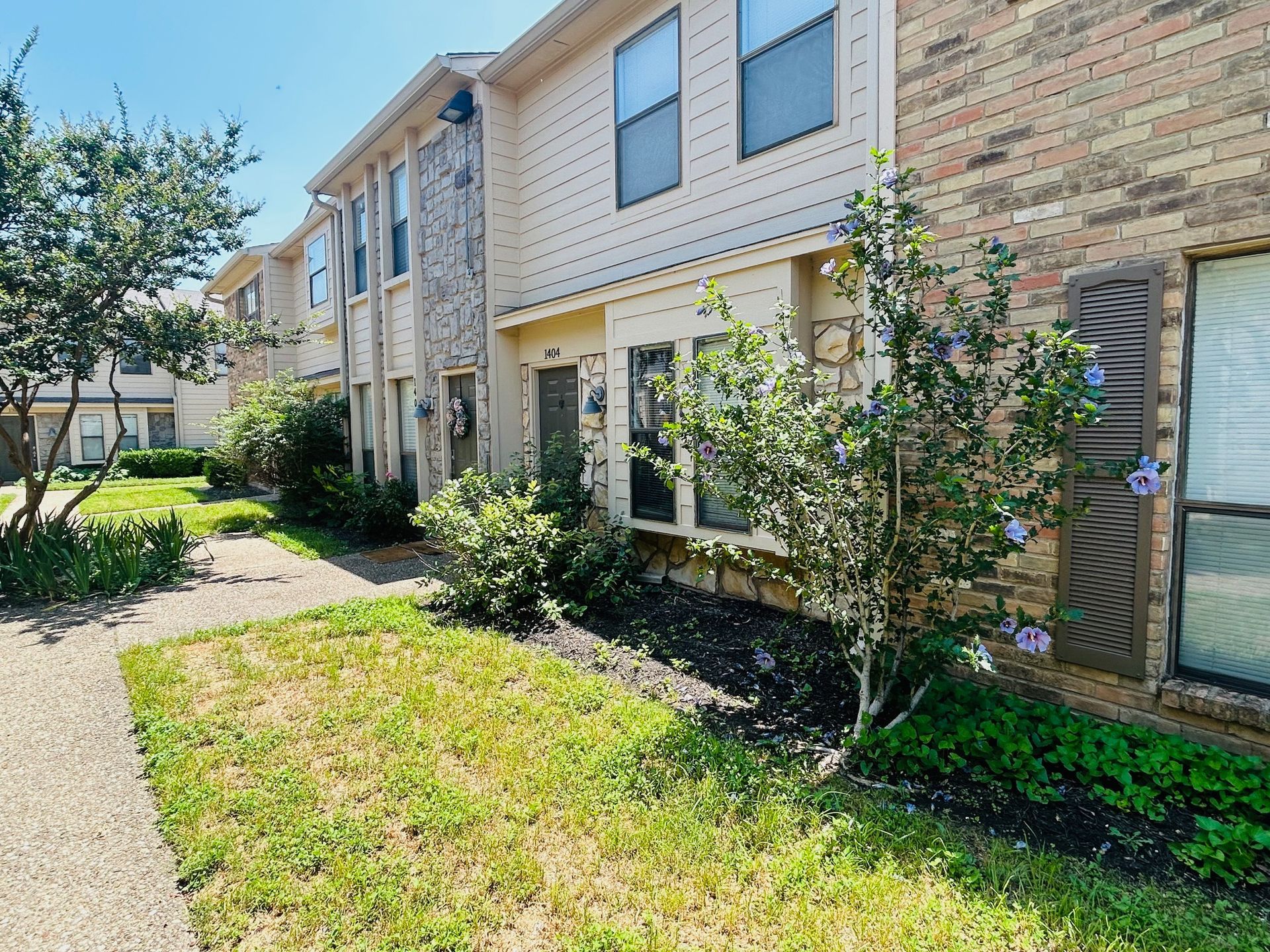 A brick apartment building with a lush green lawn in front of it.