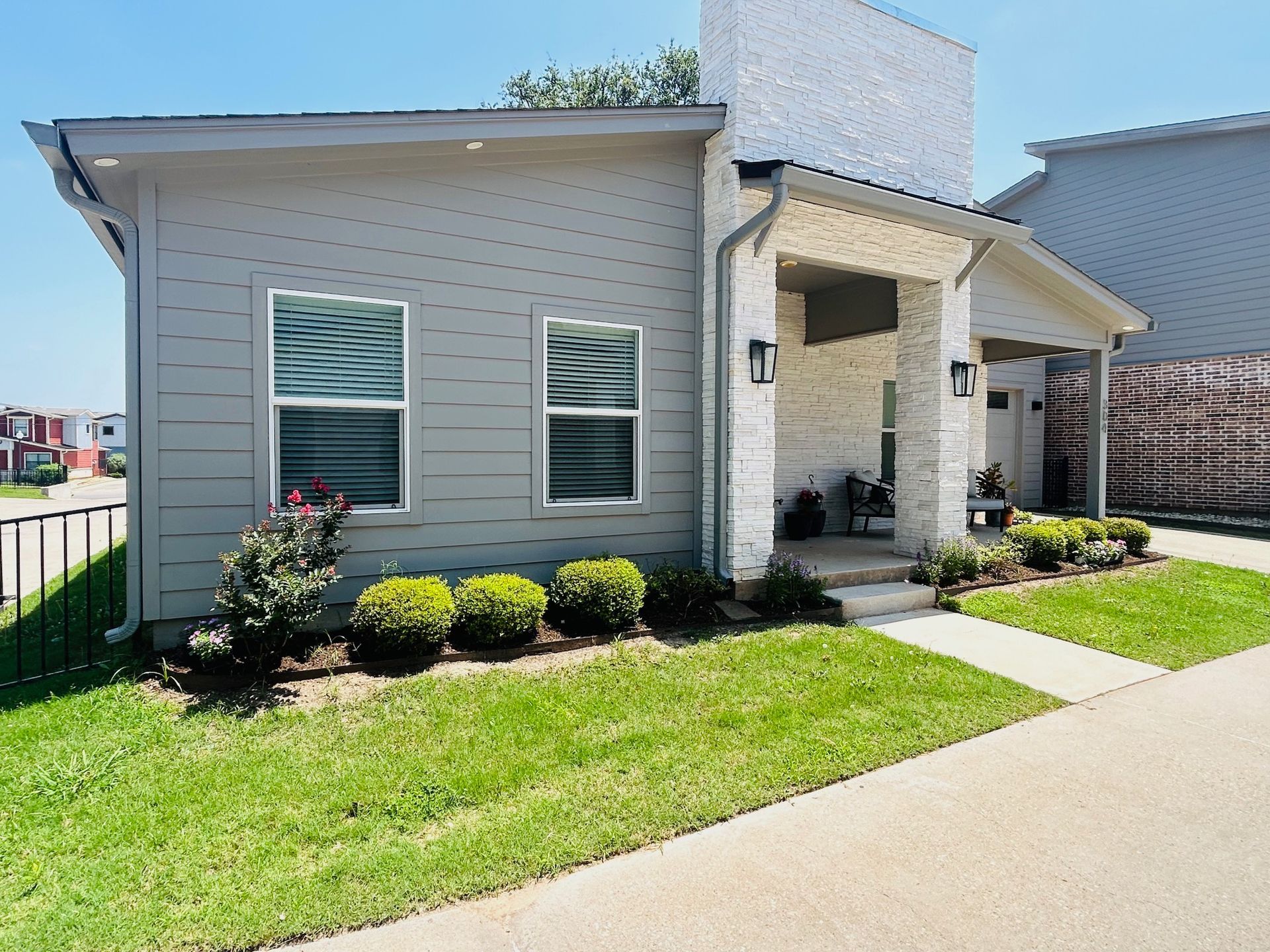 A small house with a lot of windows is sitting on a lush green lawn.