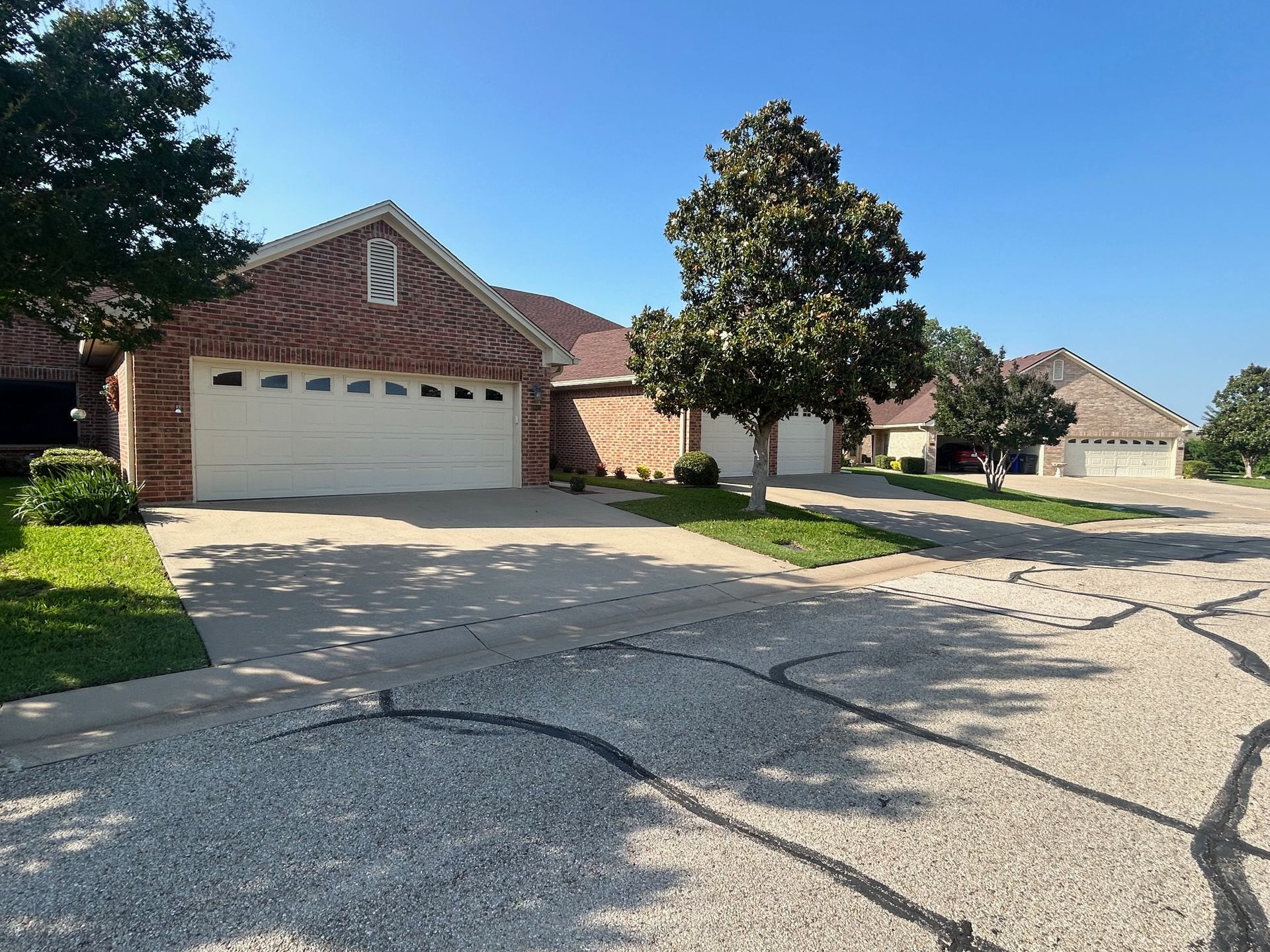 A brick house with a white garage door in a residential neighborhood