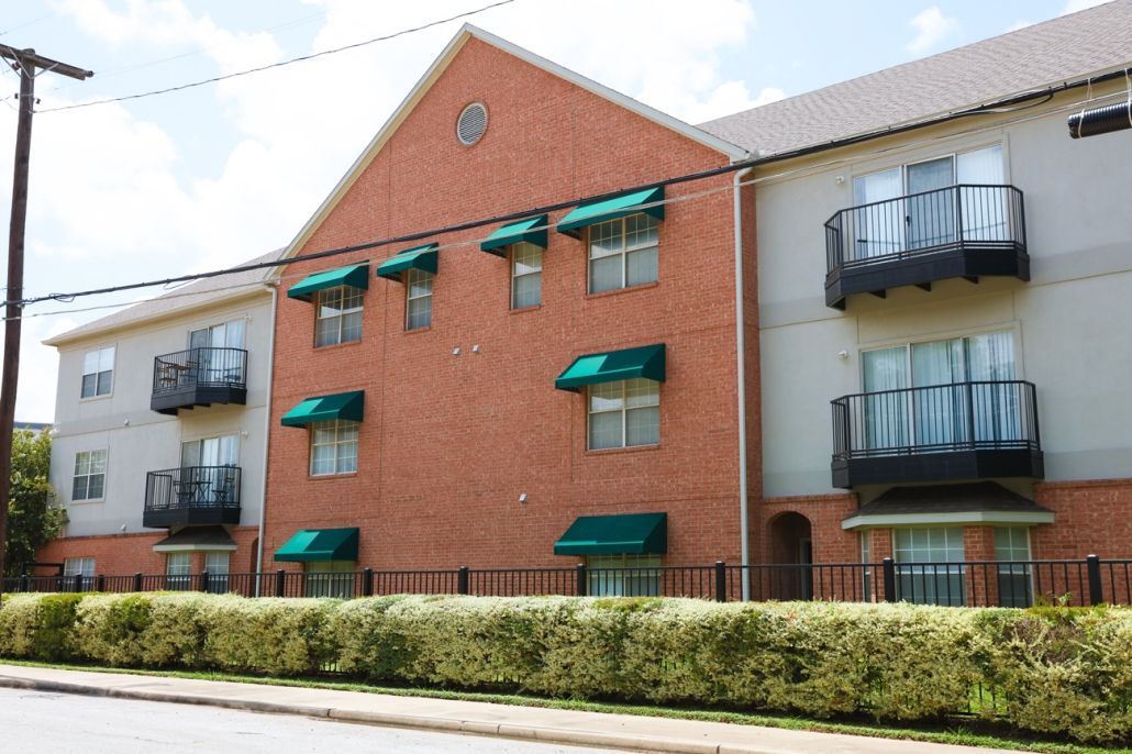 A large brick apartment building with balconies and green awnings