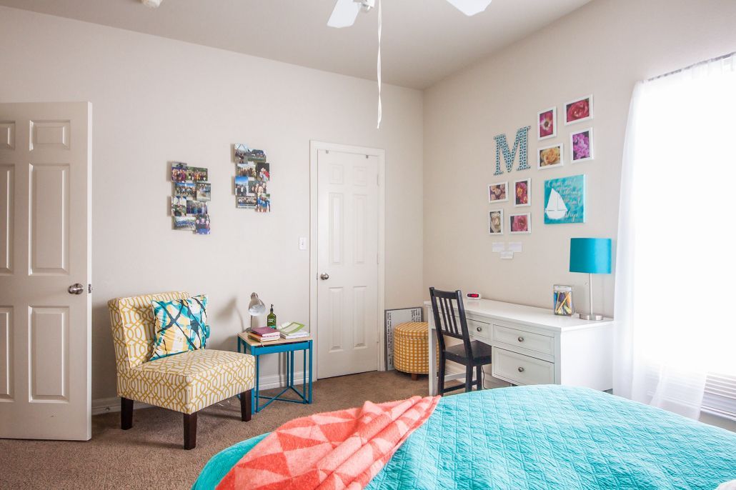 A bedroom with a bed , chair , desk and ceiling fan.