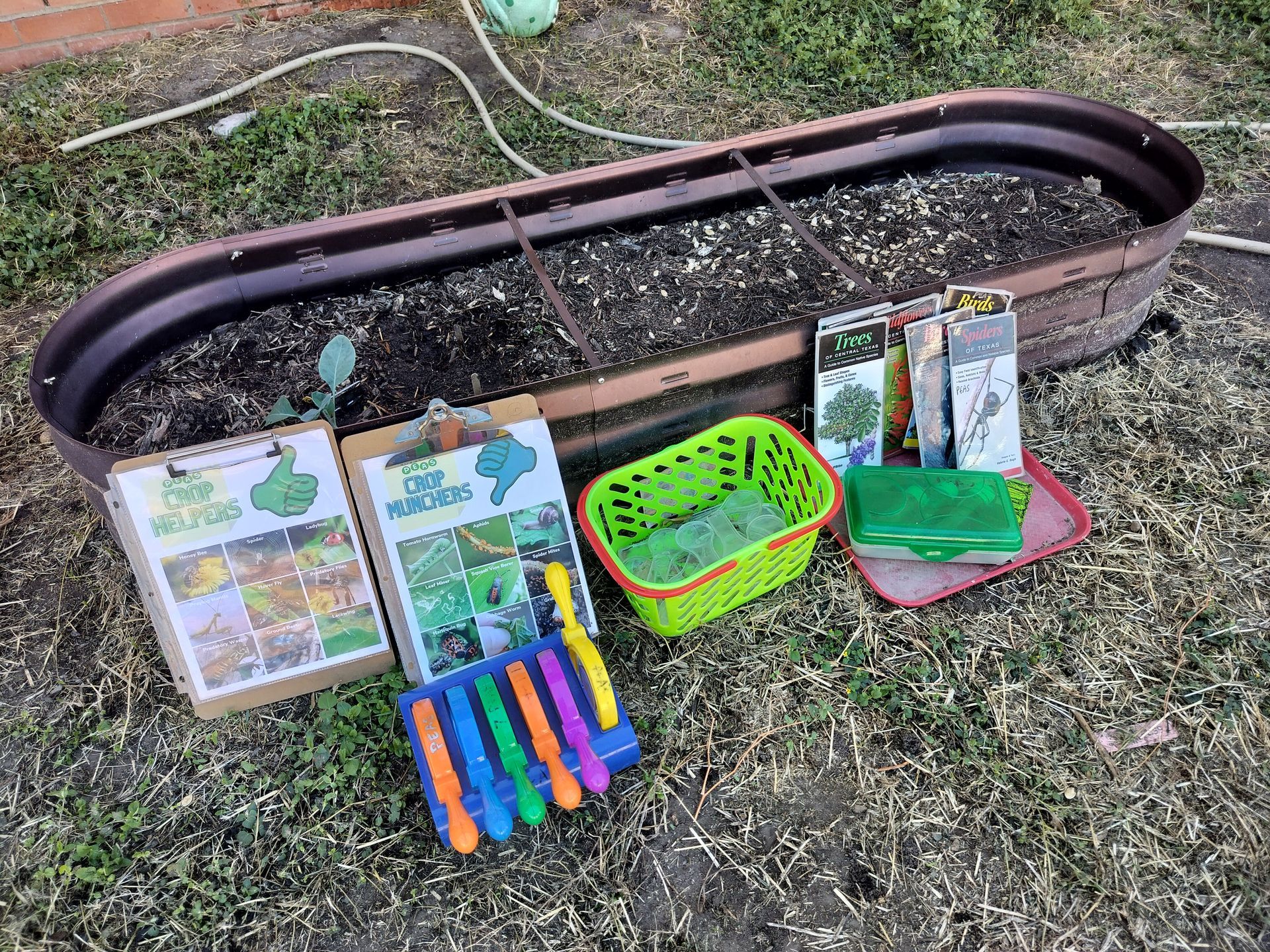 A bunch of gardening supplies are sitting on the ground next to a planter.