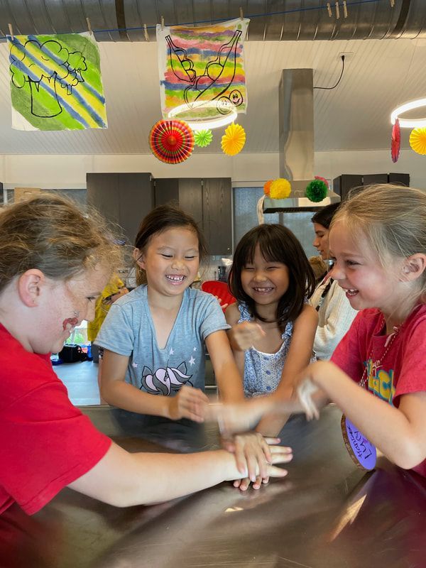 A group of young girls are putting their hands together at a table.