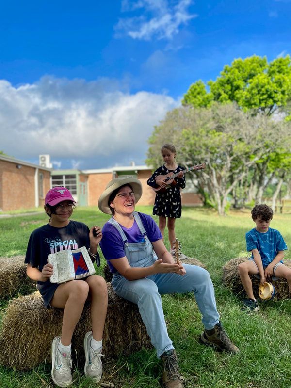 A group of children are sitting on hay bales in a field.