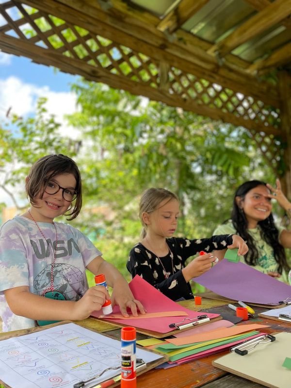 A group of children are sitting at a table making crafts.
