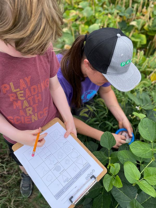 A boy and a girl are looking at a plant with a clipboard.