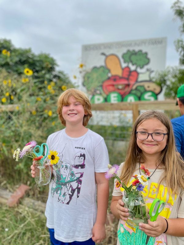 A boy and a girl are holding flowers in front of a sign.