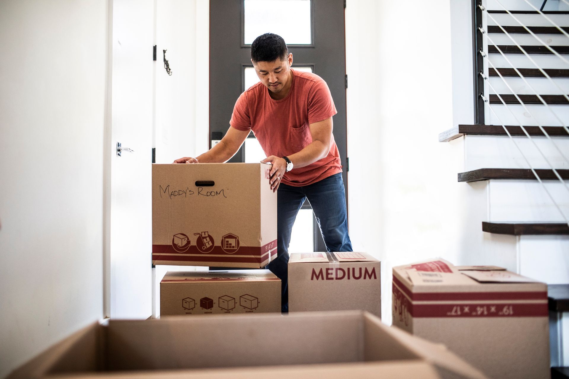 Man organizing boxes during stress-free moving and cleaning process inside modern home.