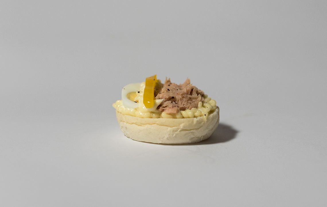 Piccolo antipasto di insalata di tonno su una base di pane bianco, con uovo e peperone giallo.