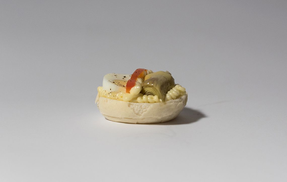 Mini antipasto, piccola base di pane farcita con insalata di uova, carciofi e peperoni rossi.