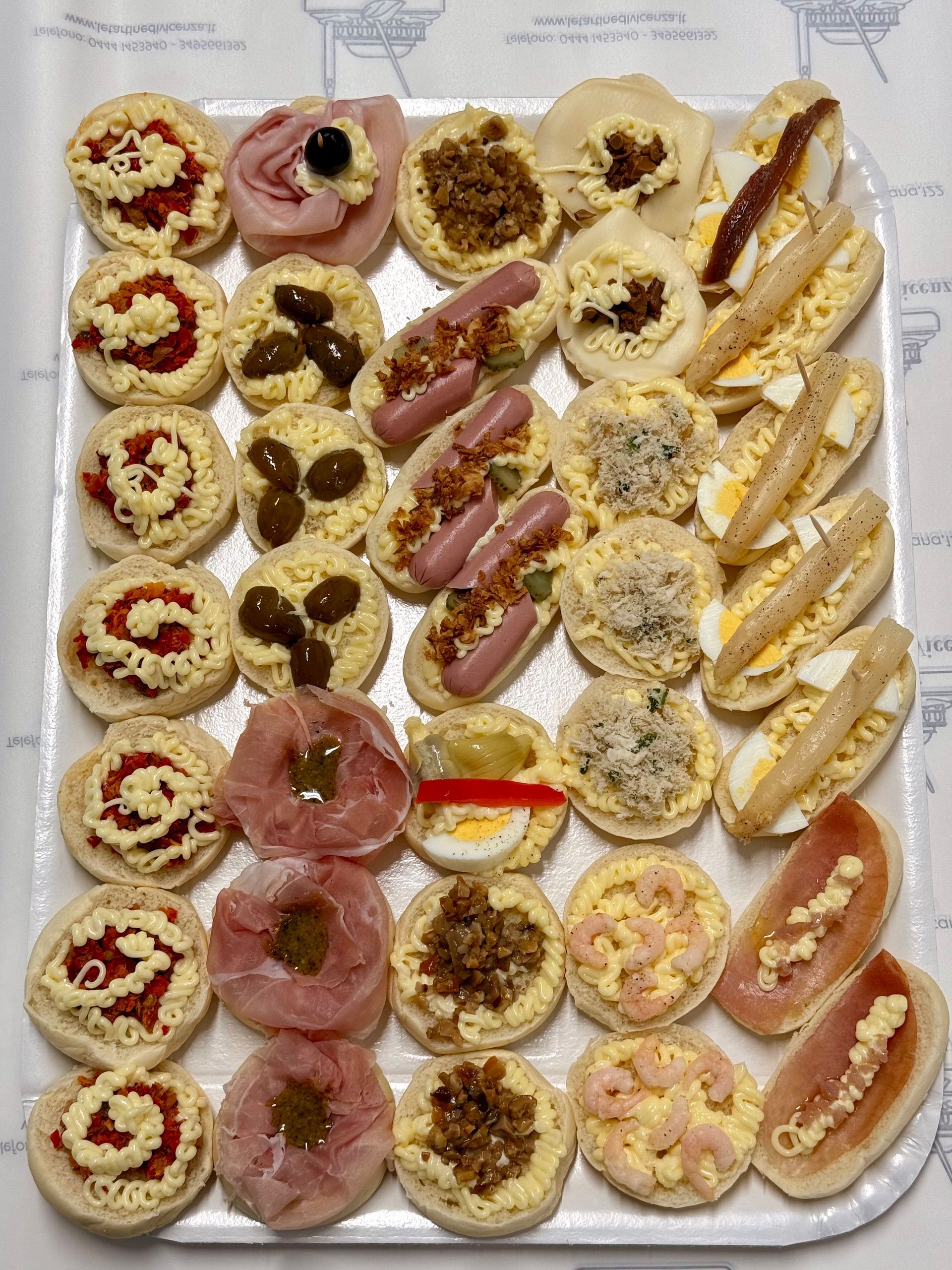 Un vassoio di tartine assortite, vari condimenti su piccole fette di pane e panini.