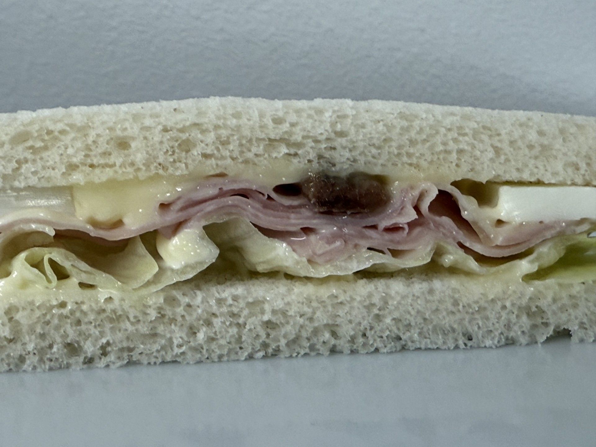Panino al prosciutto con lattuga e formaggio su pane bianco.