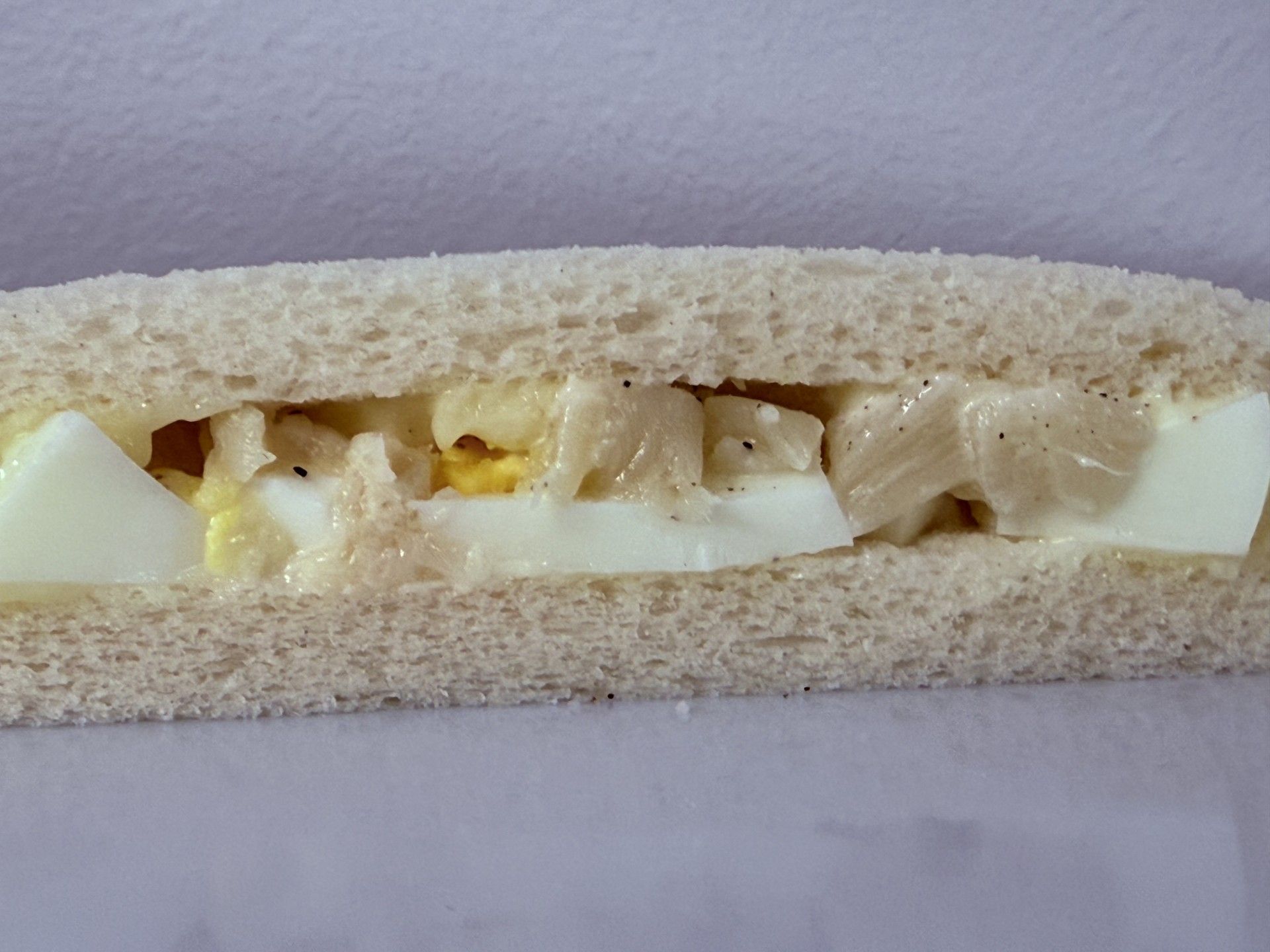 Panino con insalata di uova su pane bianco tagliato a metà.