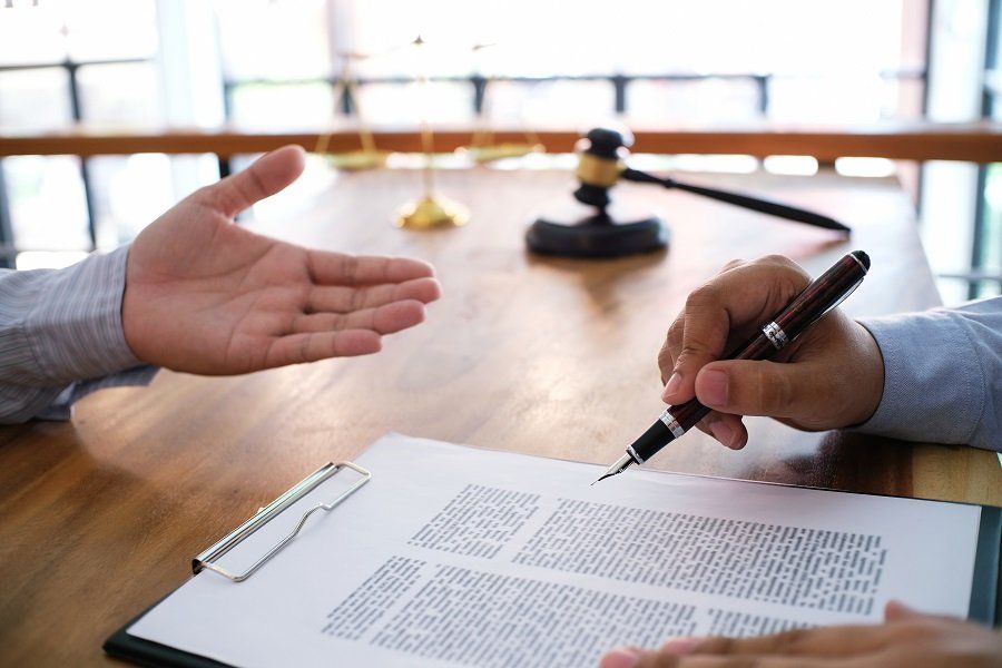 an attorney holding a pen over legal notes while conversing with a client