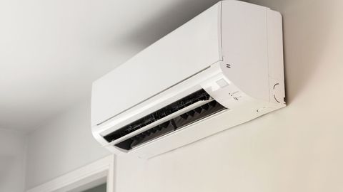 A white air conditioner is hanging on a wall in a room.