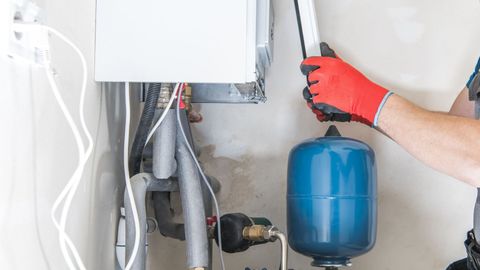 A man is installing a water heater in a house.