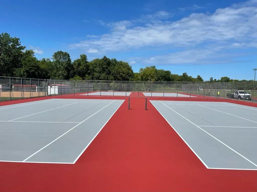 A tennis court with a fence and trees in the background