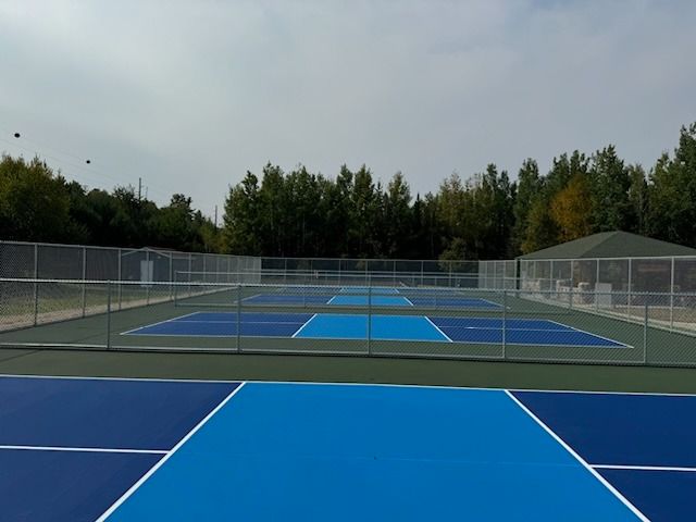 A blue tennis court with a fence around it