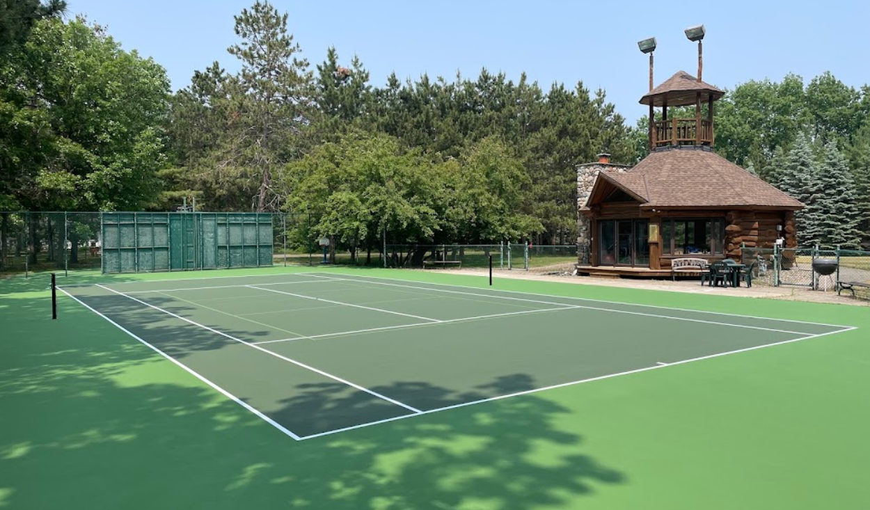 A tennis court with a log cabin in the background