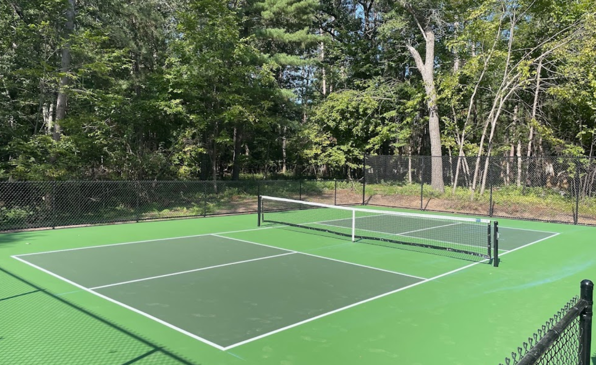 A tennis court with a net and trees in the background.