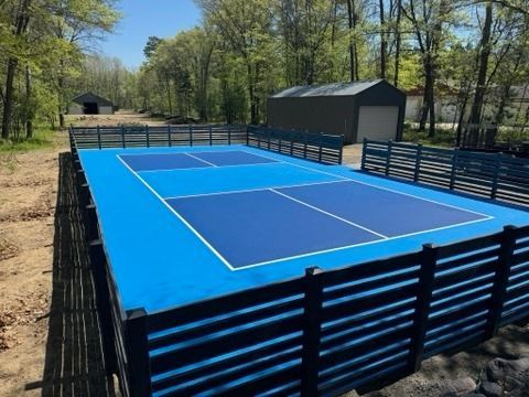 A blue tennis court with a black fence around it