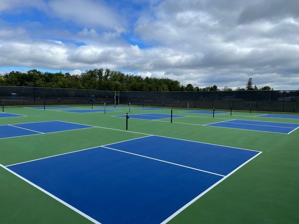 A tennis court with blue and green courts on a cloudy day