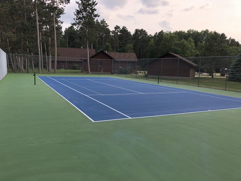 A tennis court with a fence and trees in the background
