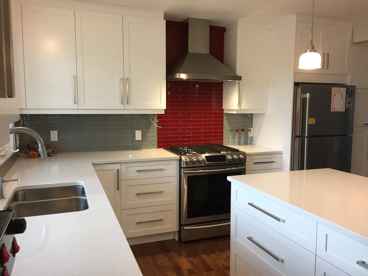 Une cuisine avec des armoires blanches et des appareils électroménagers en acier inoxydable