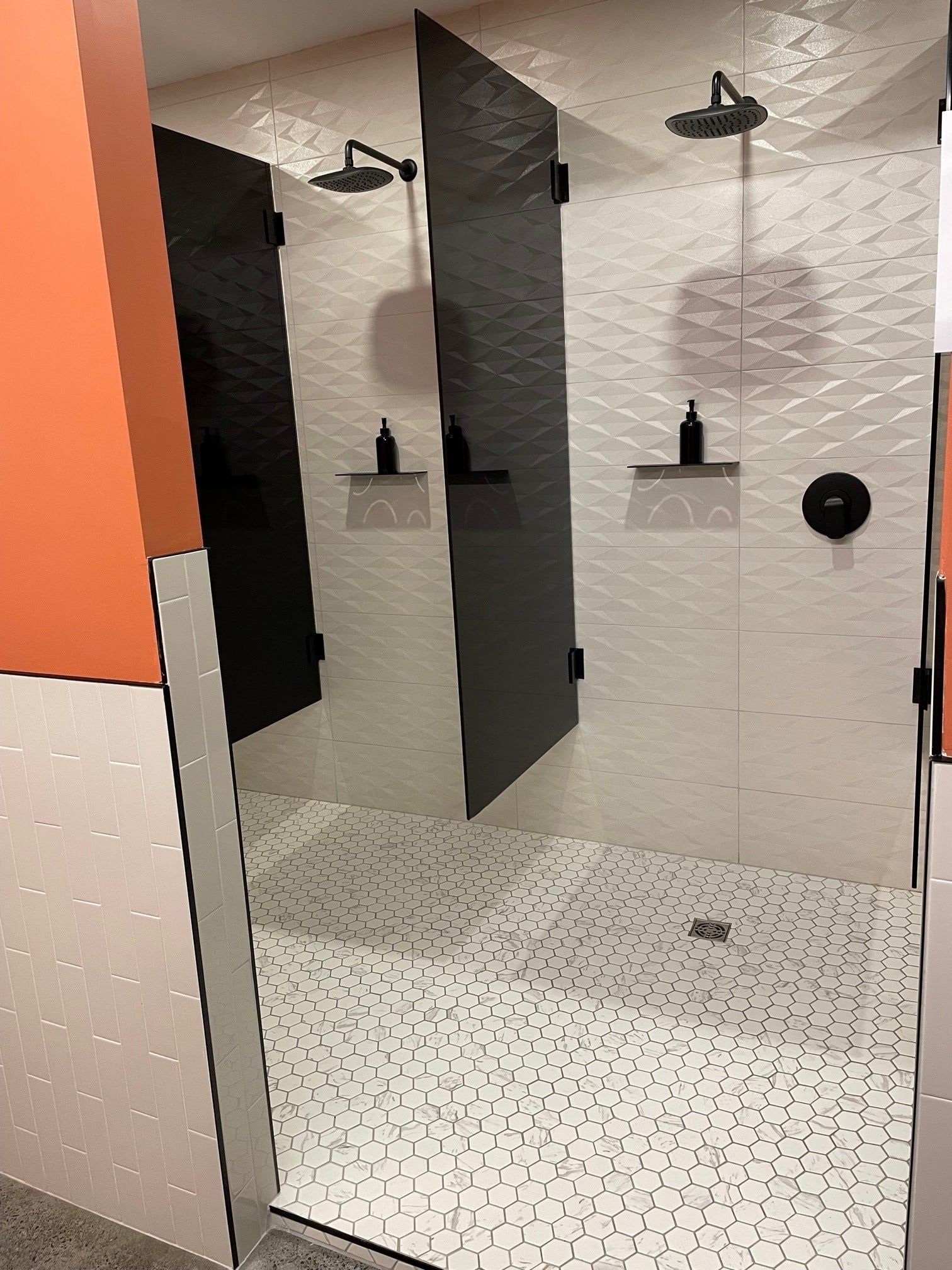 Une salle de bain avec deux cabines de douche et un pommeau de douche.