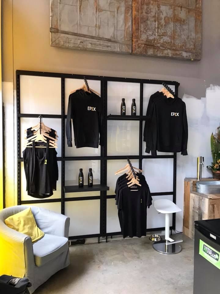 Un salon avec un canapé et une étagère sur laquelle sont accrochées des chemises