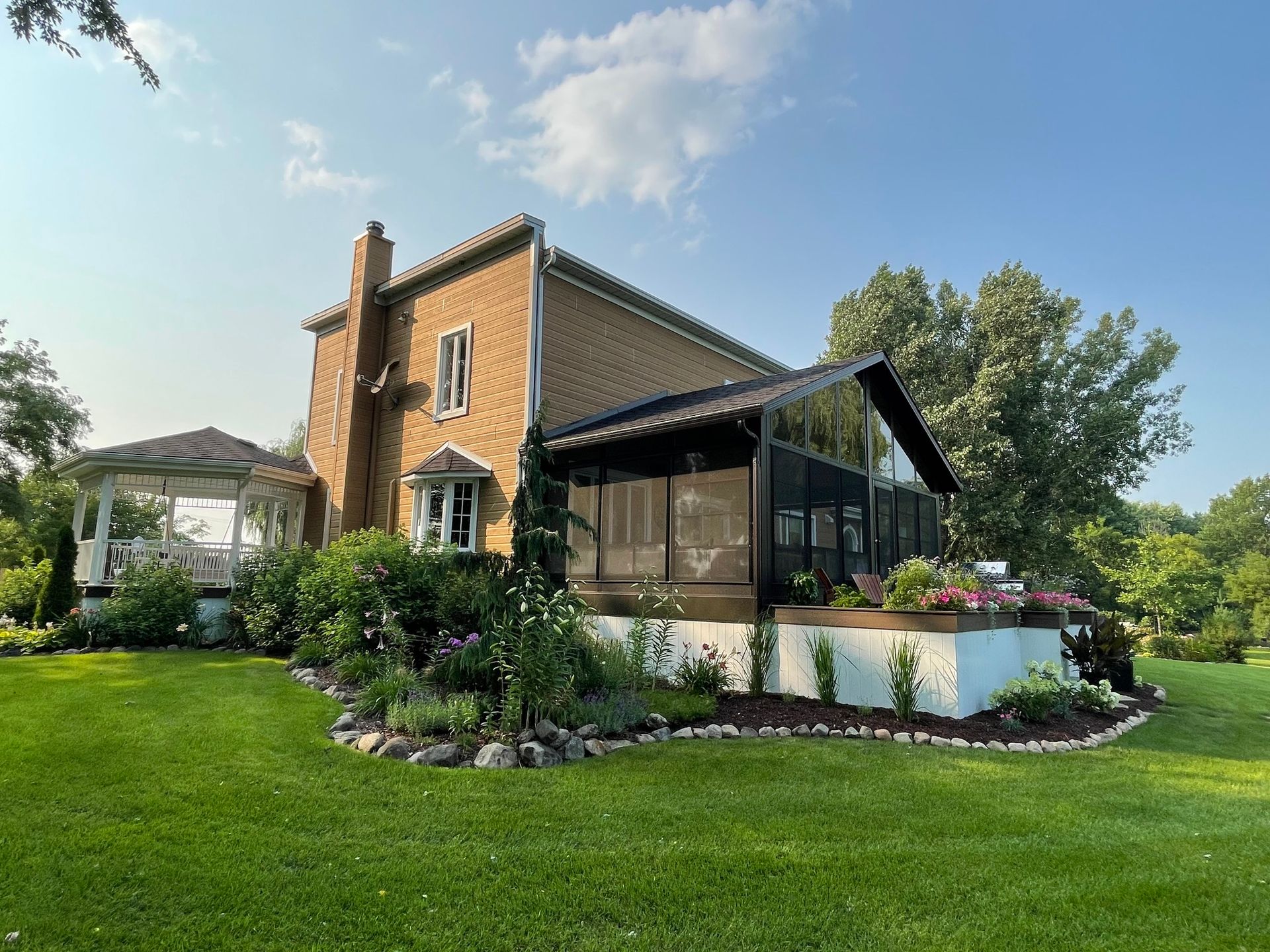 Une grande maison en brique avec une véranda grillagée dans la cour.
