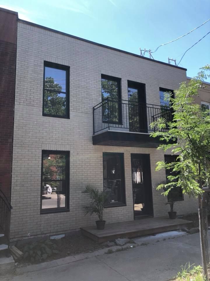 Un bâtiment en briques blanches avec des fenêtres noires et un balcon