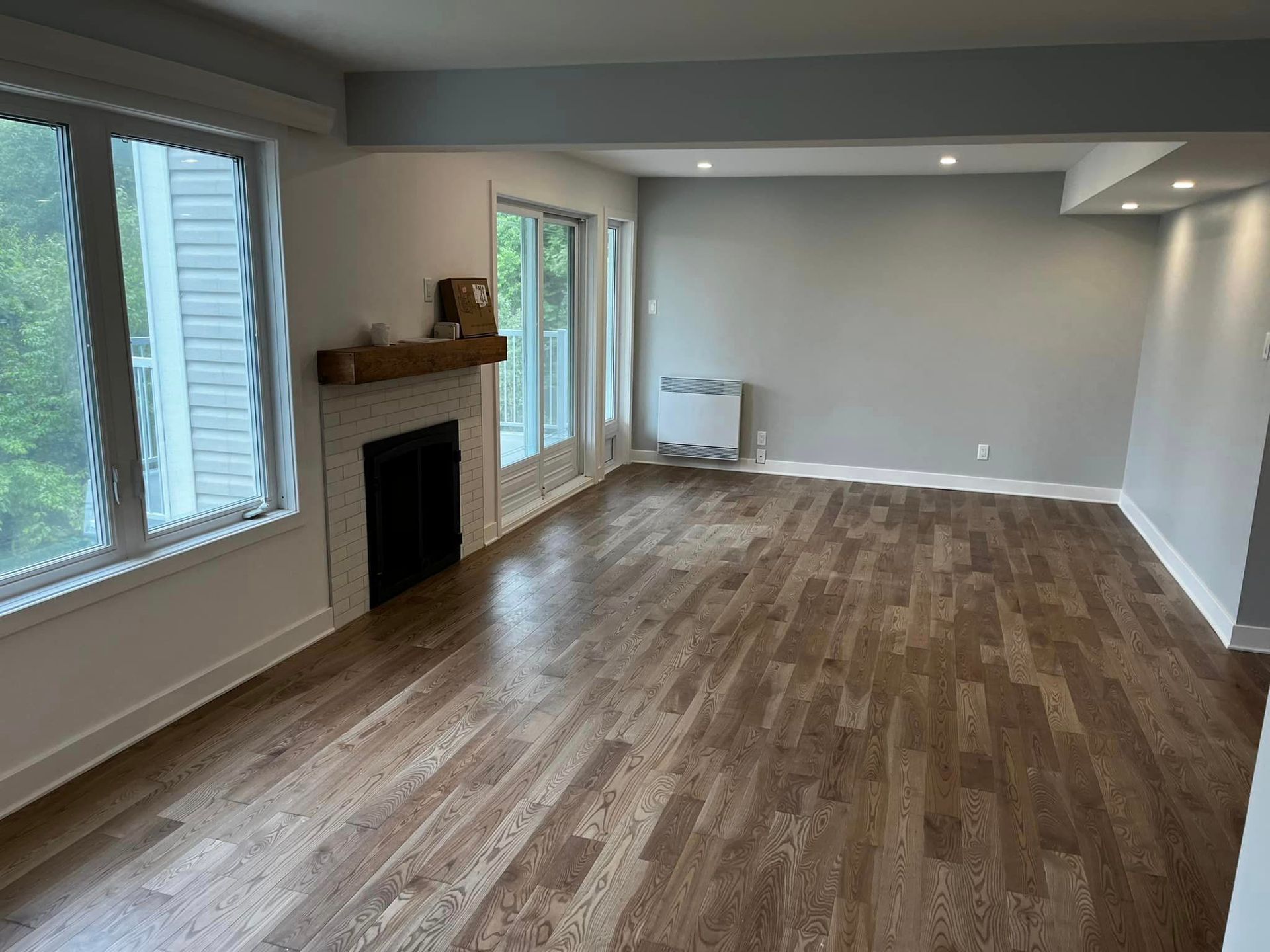 Un salon vide avec parquet et cheminée.