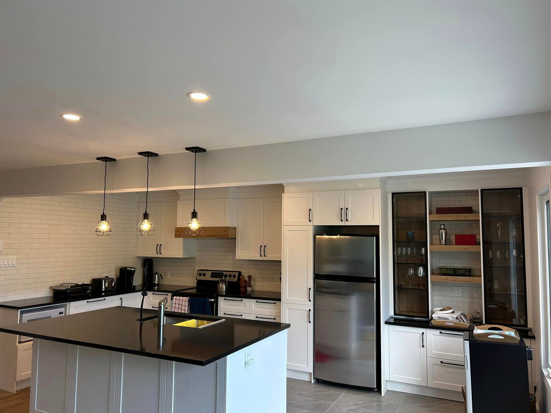 Une cuisine avec armoires blanches, appareils électroménagers en acier inoxydable et un grand îlot.