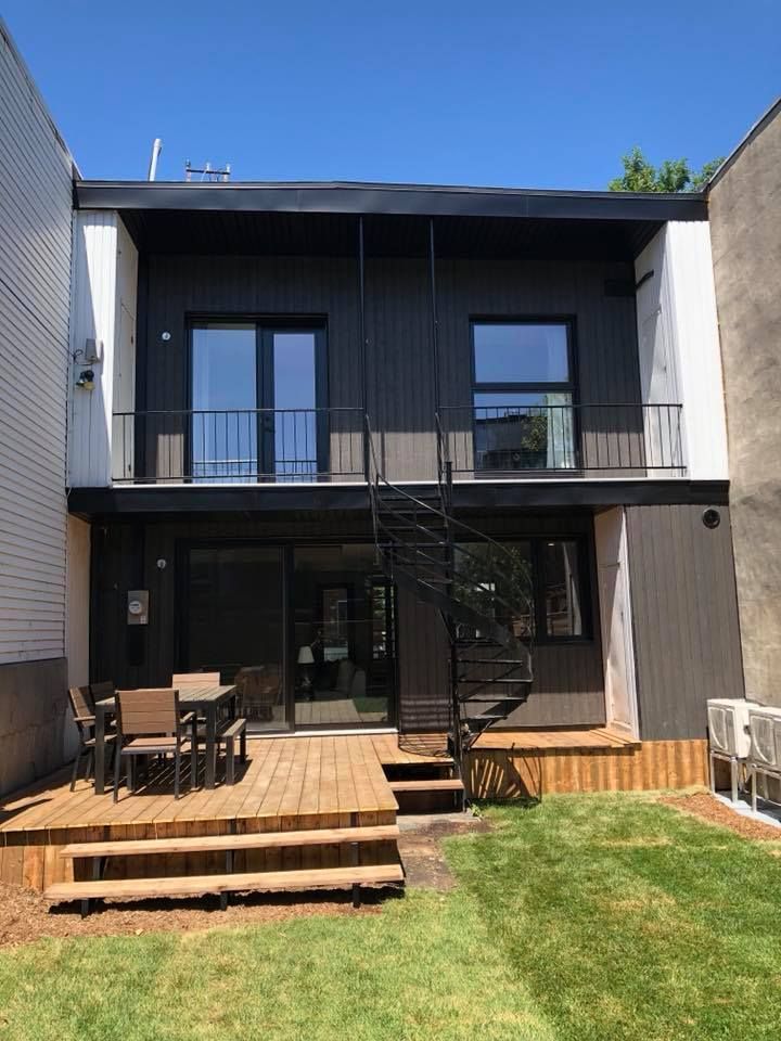 L'arrière d'une maison avec un escalier en colimaçon et une terrasse.