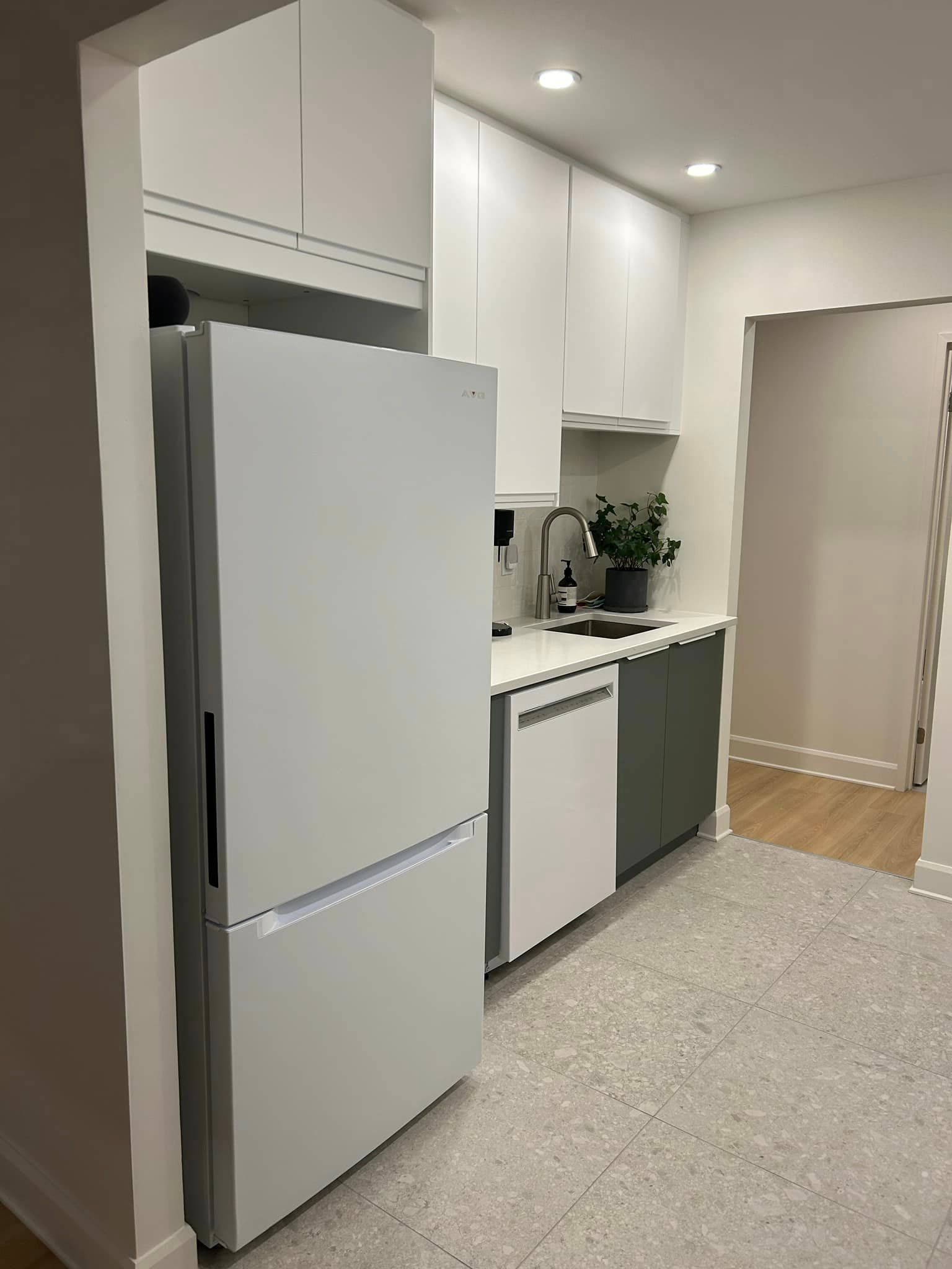 Une cuisine avec des armoires blanches et un réfrigérateur blanc.