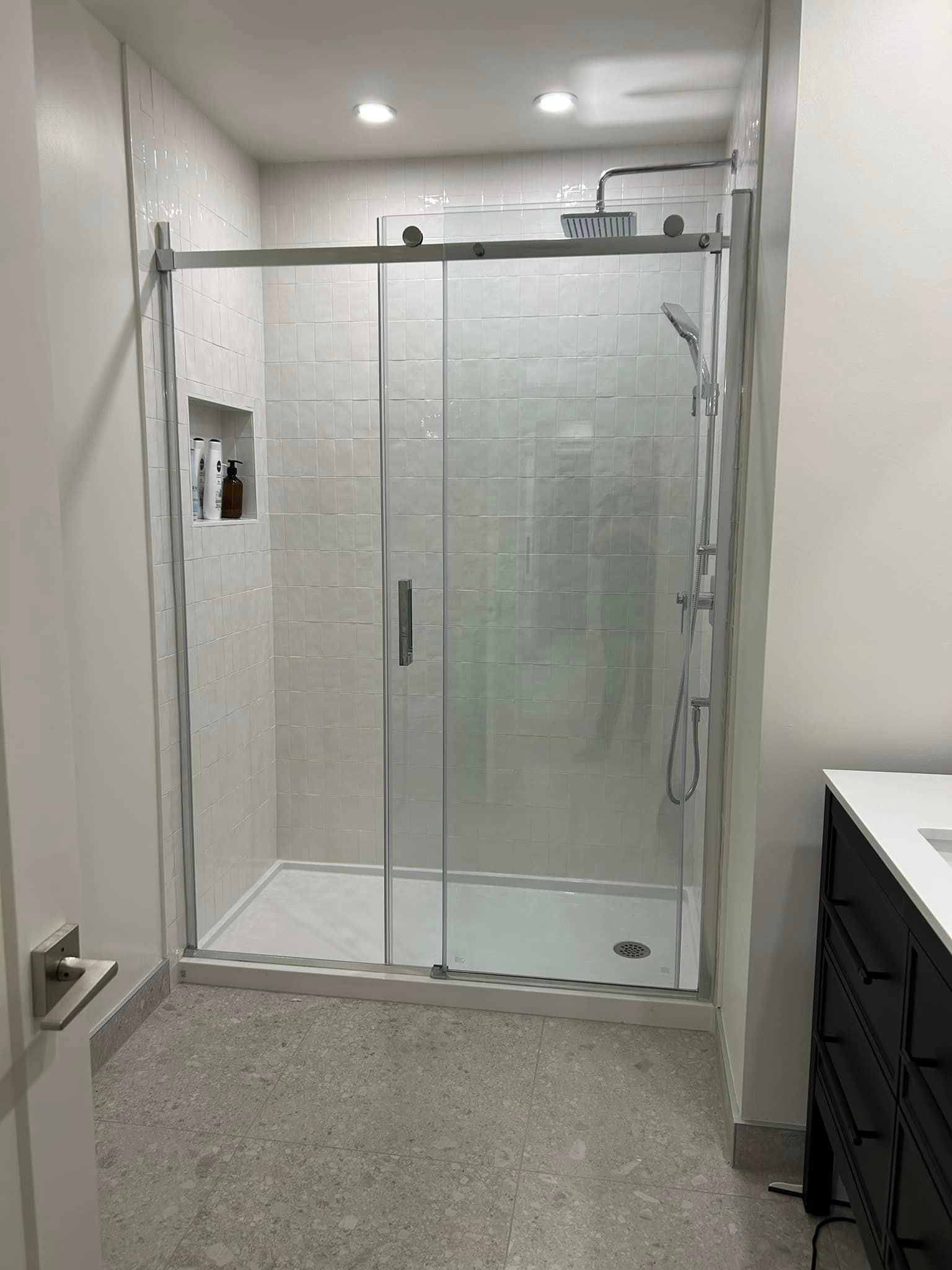 Une salle de bain avec une porte de douche coulissante en verre et un lavabo.