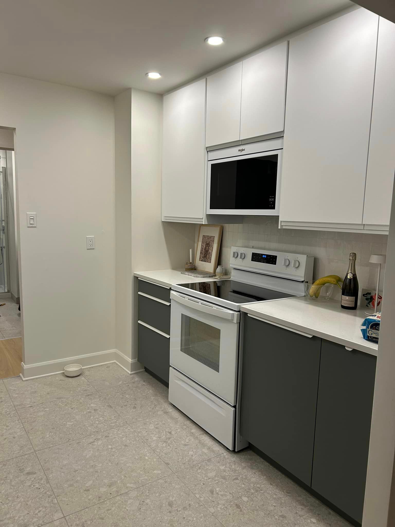 Une cuisine avec des armoires blanches, une cuisinière blanche, un micro-ondes et un évier.