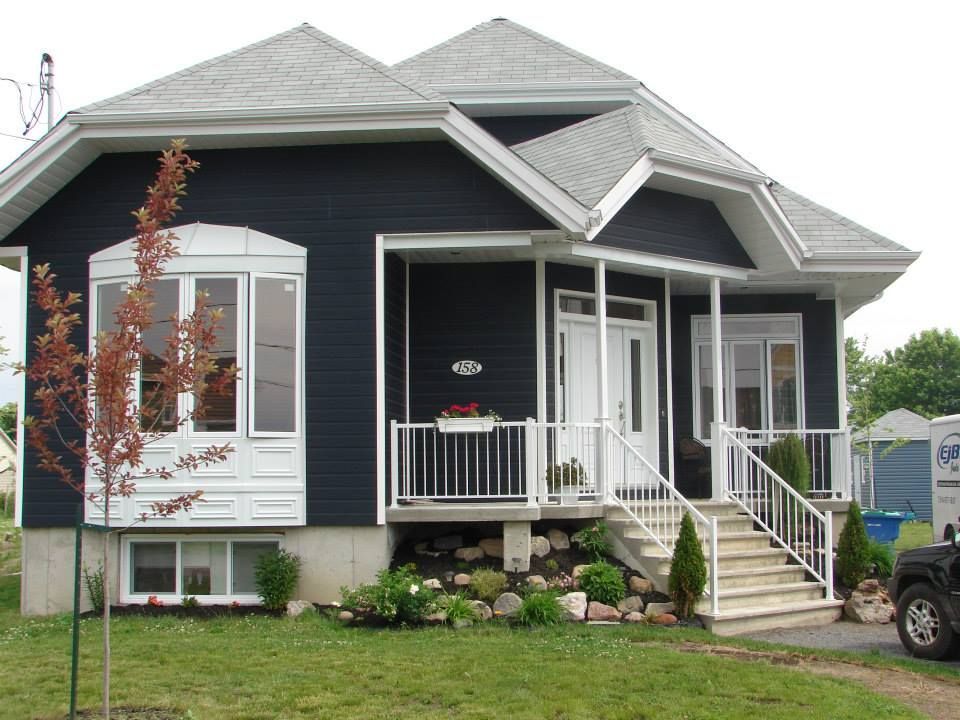 Une maison en noir et blanc avec un camion blanc garé devant