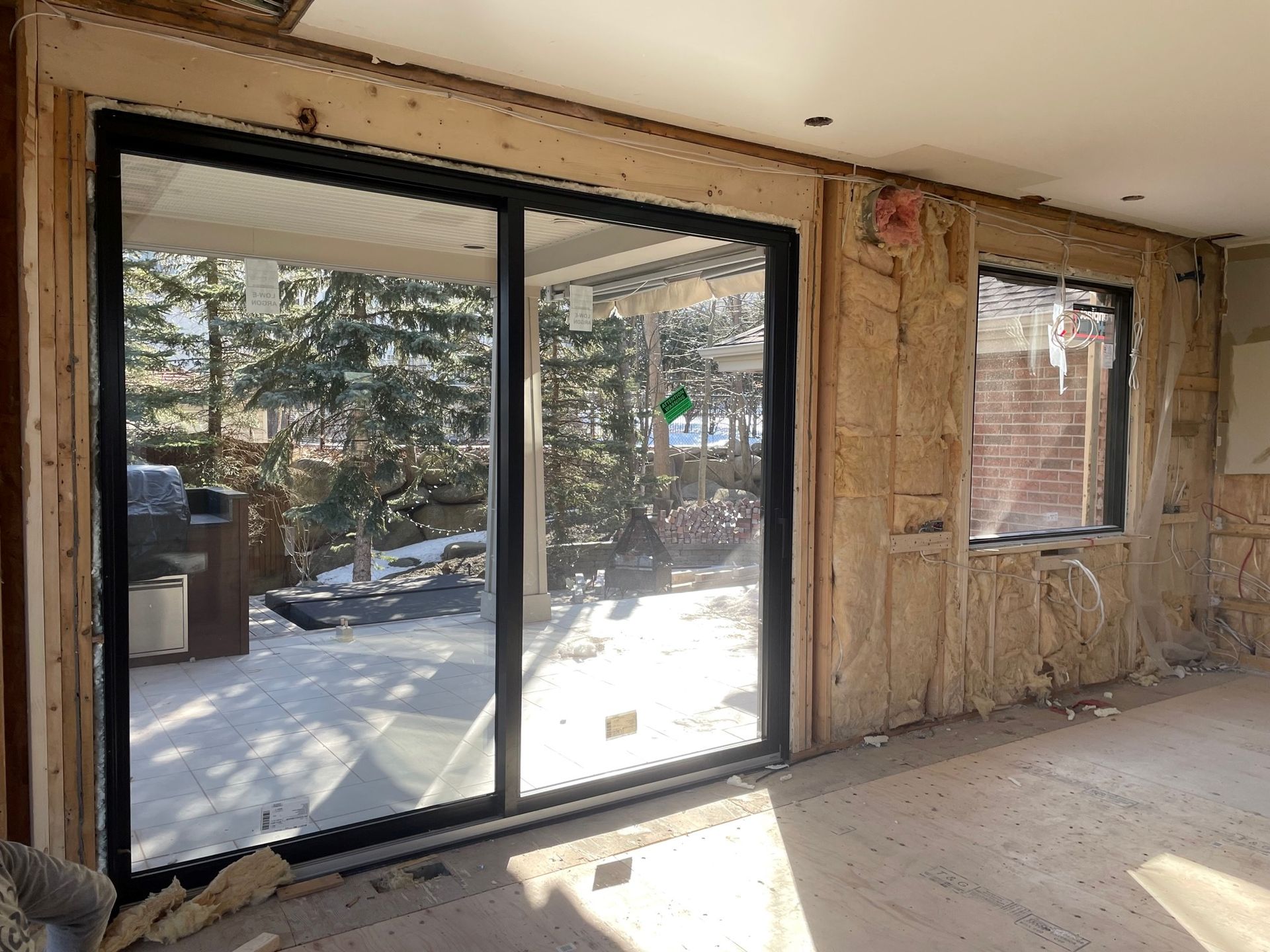 Vue intérieure d'une pièce avec une porte coulissante à cadre noir et une fenêtre donnant sur une cour arrière enneigée.