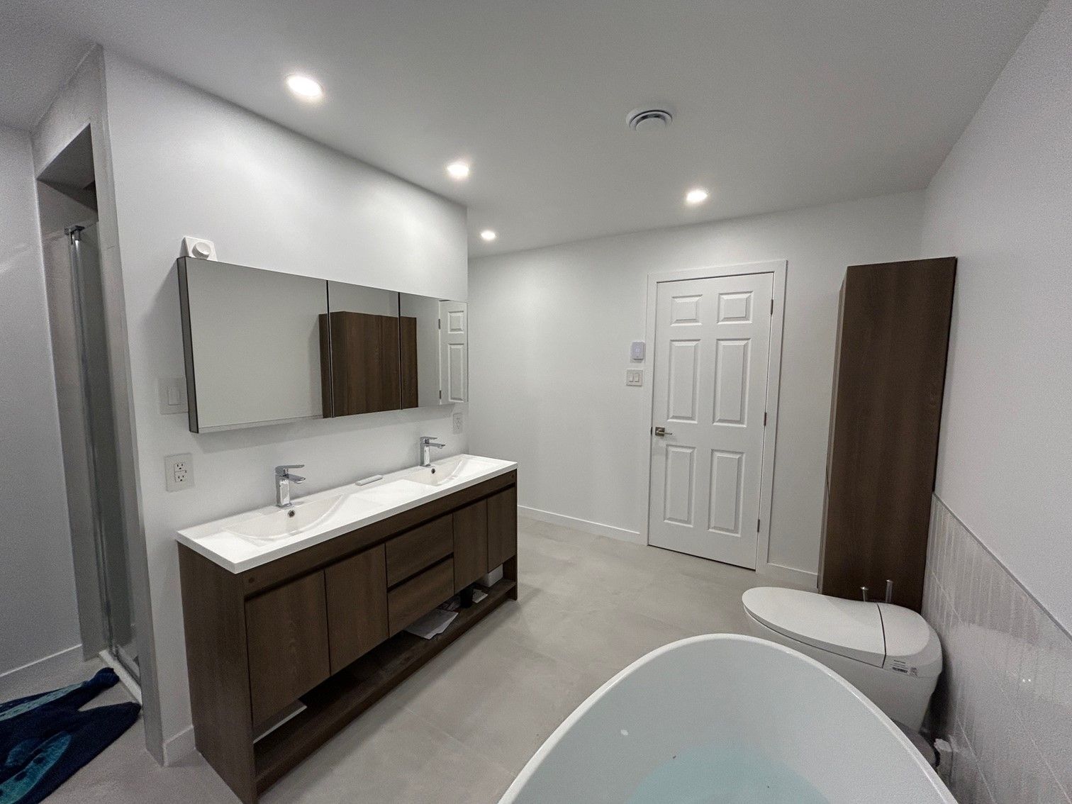 Salle de bain moderne avec double vasque, baignoire profonde et une grande armoire de rangement.